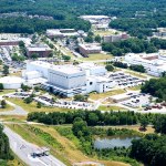 Aerial image of Goddard Greenbelt campus showing white and brick buildings amidst green trees.