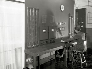 Man in suit sitting in control room.