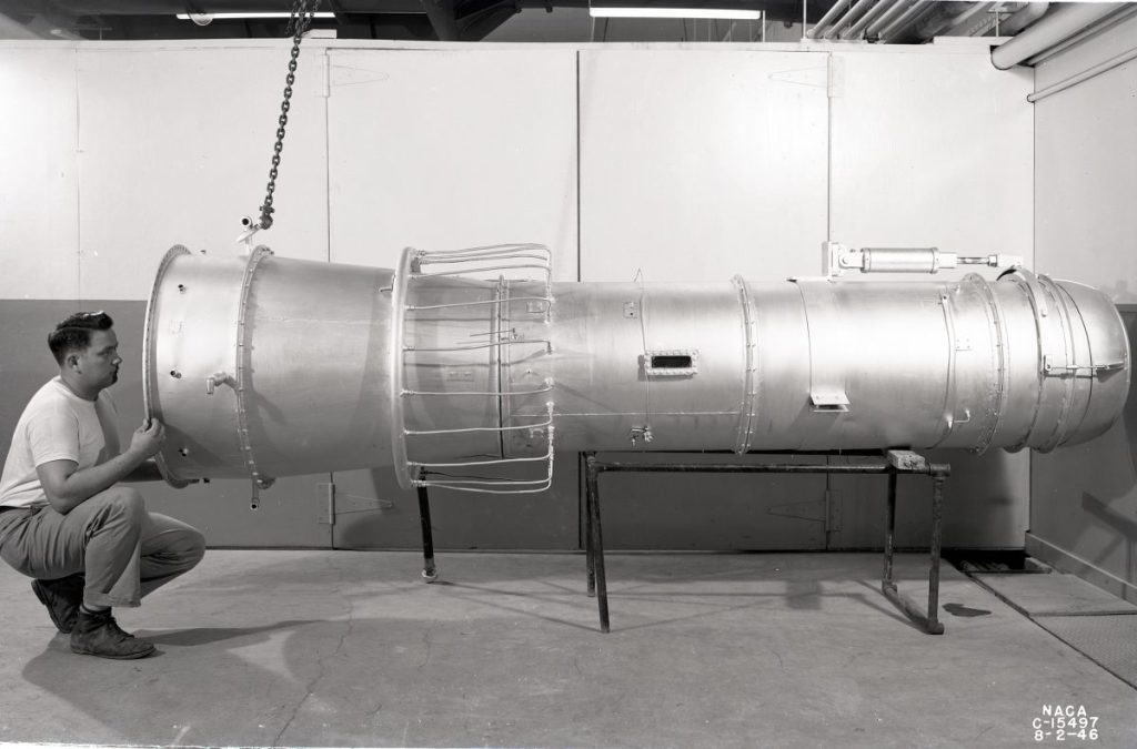 Man squatting to look into jet engine.