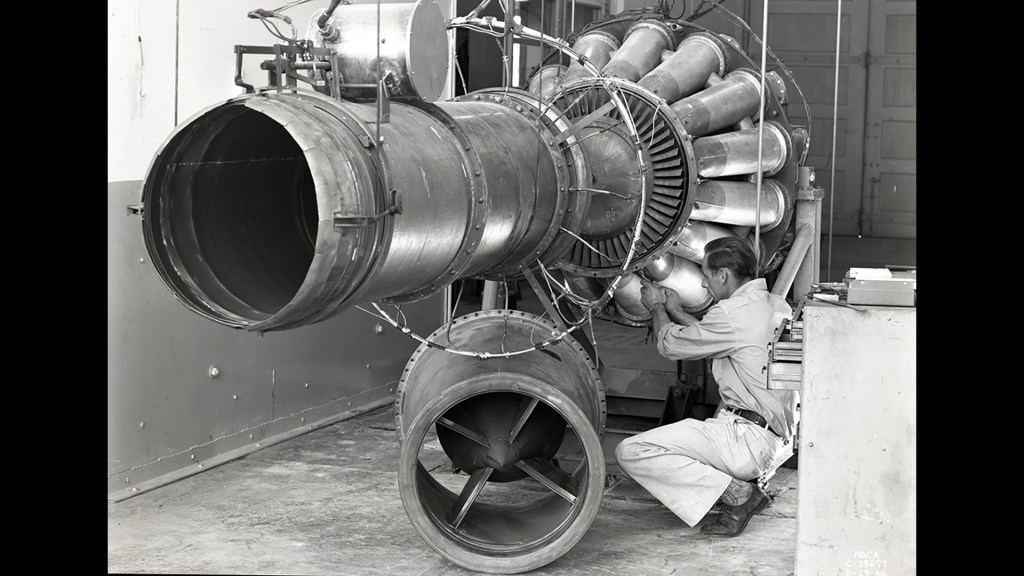 Man in overalls working on engine.