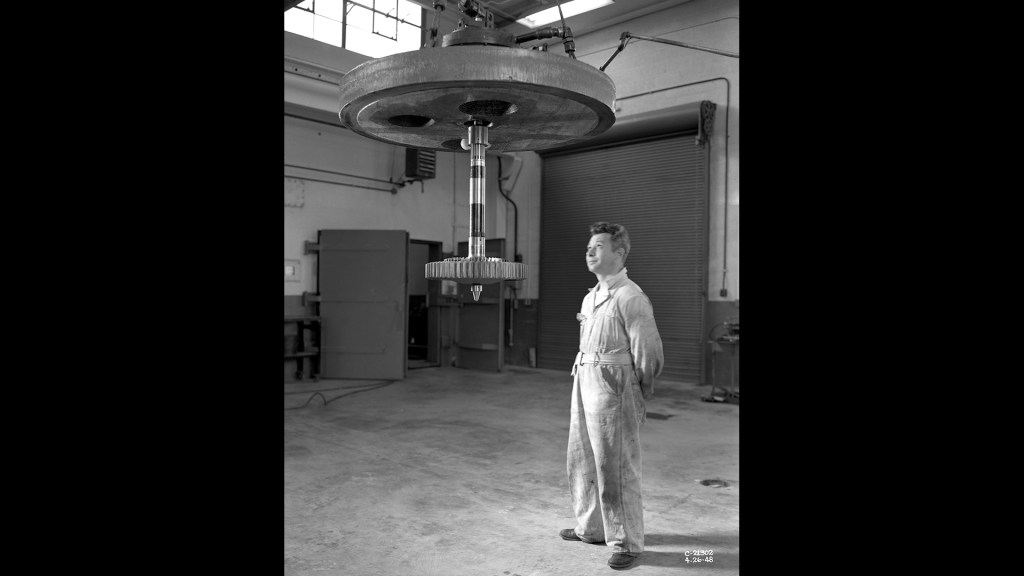 Mechanic watches spin equipment suspended from crane.