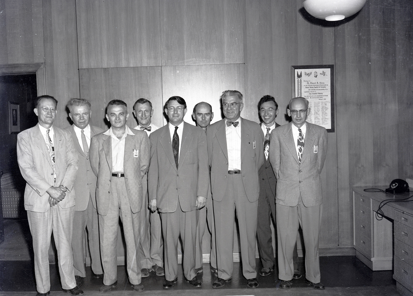 Group of men standing against office wall.