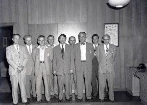 Group of men standing against office wall.