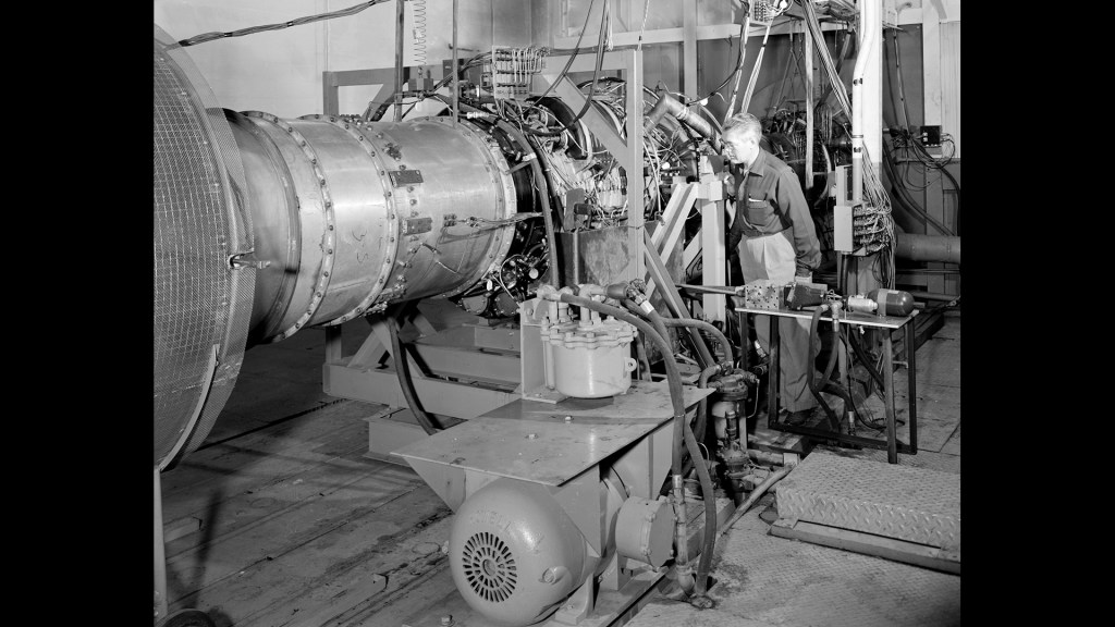 Mechanic inspects J-65 engine in test cell.