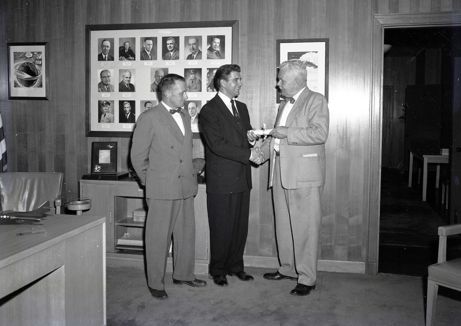 Three men standing in office.