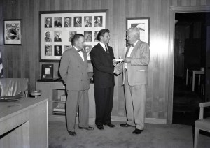 Three men standing in office.