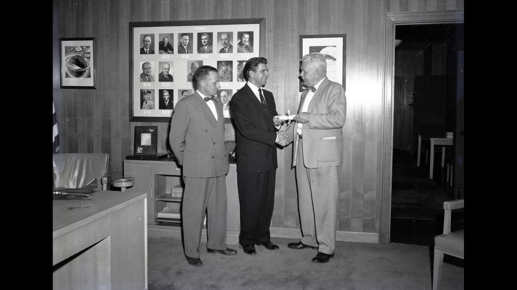 Three men standing in office.