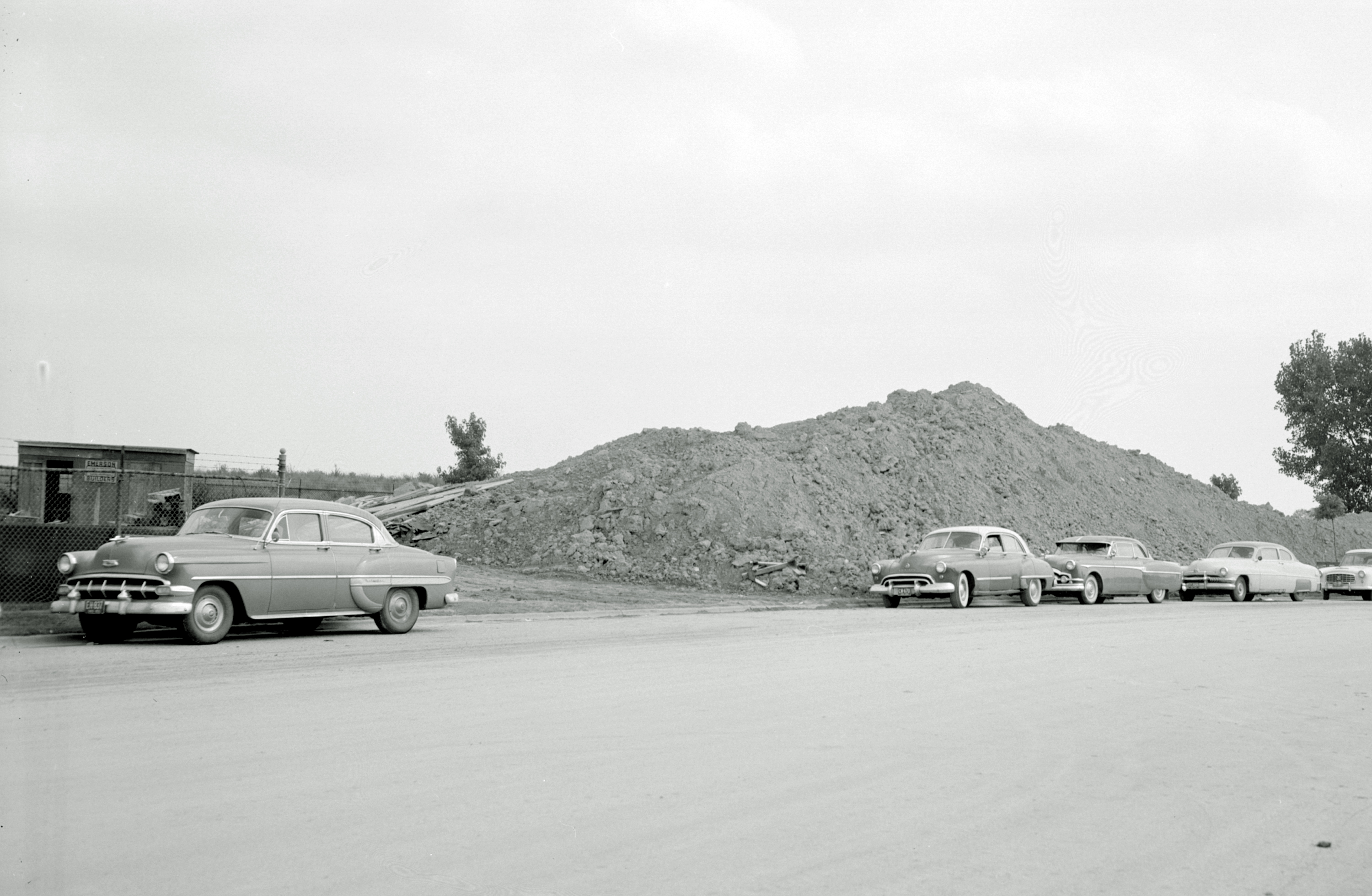 Car parked in front of mound of dirt.