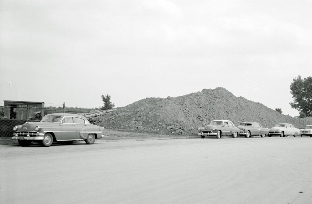 Car parked in front of mound of dirt.