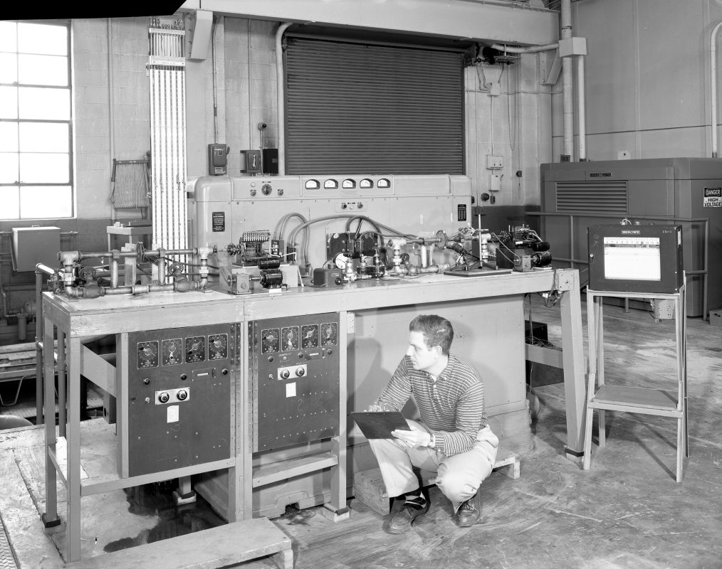 Man squatting in lab with clipboard.
