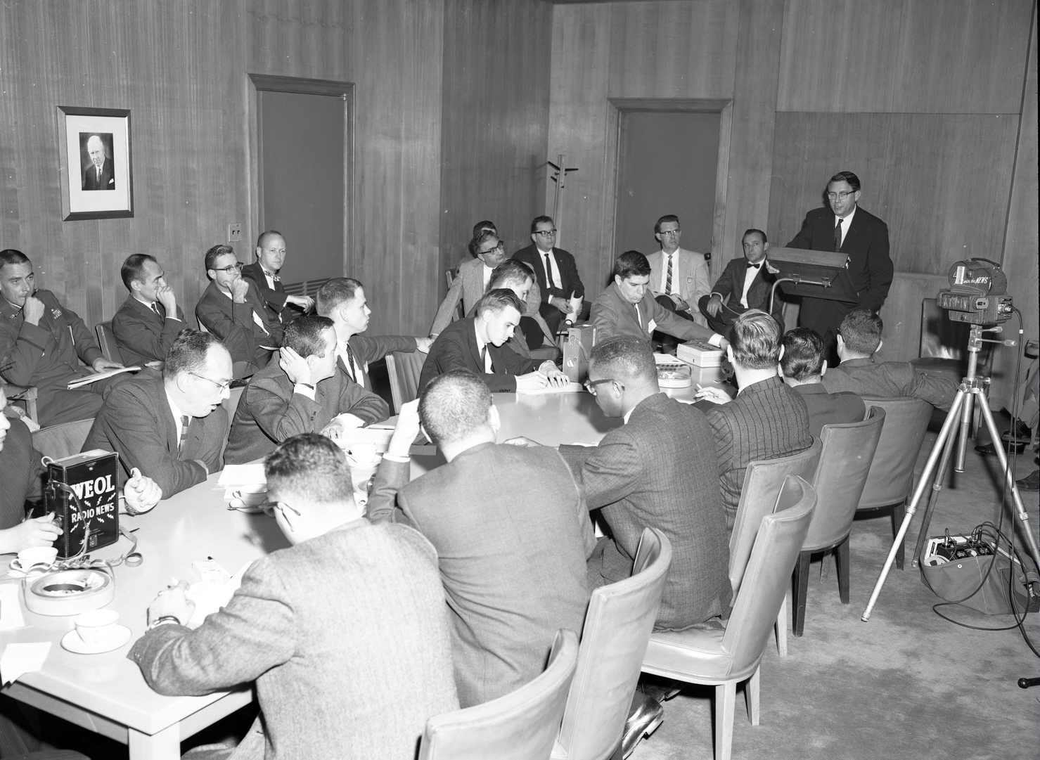 Man addressing people seated at table.