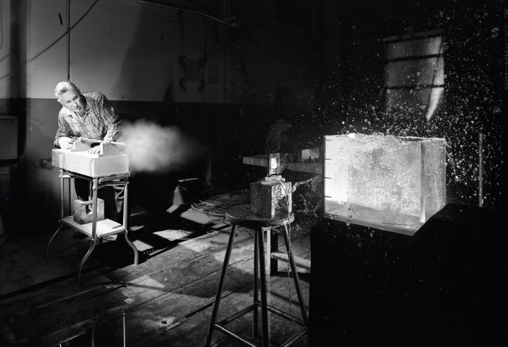 Man firing projectile at glass tank.