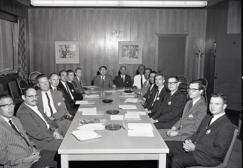 Men seated at rectangular table.