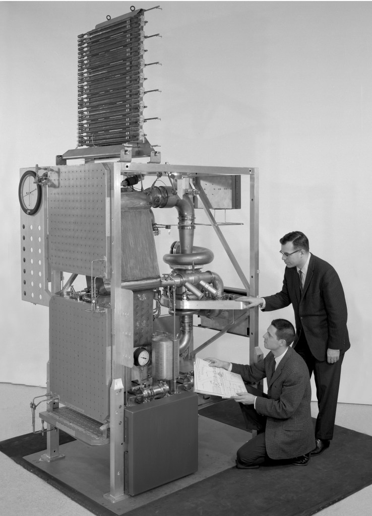 Two engineers examine Brayton rig assembly.