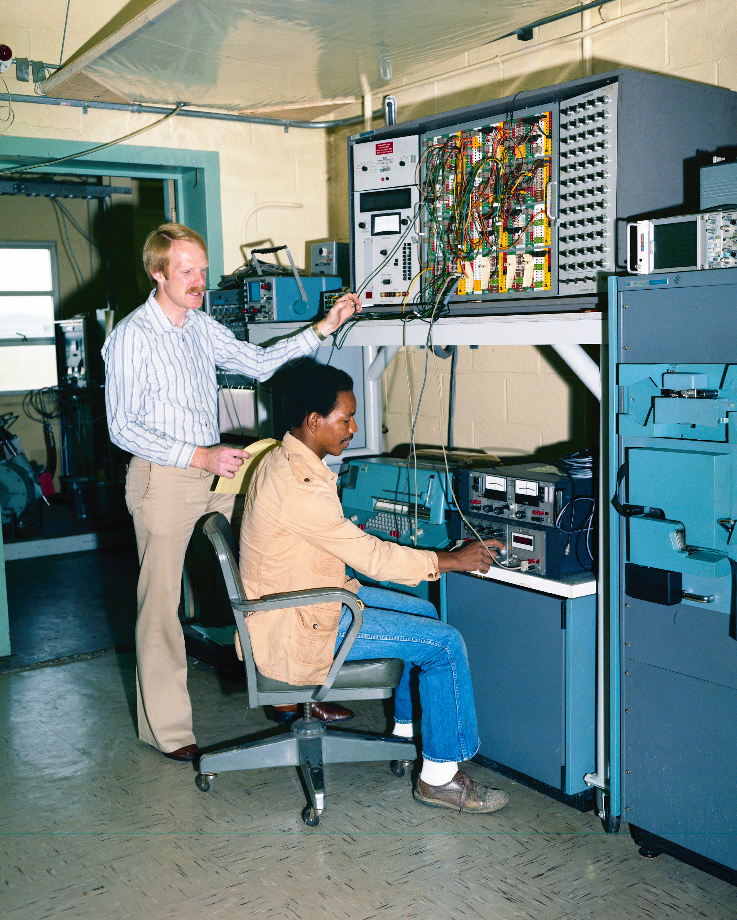 Two men at control panel.