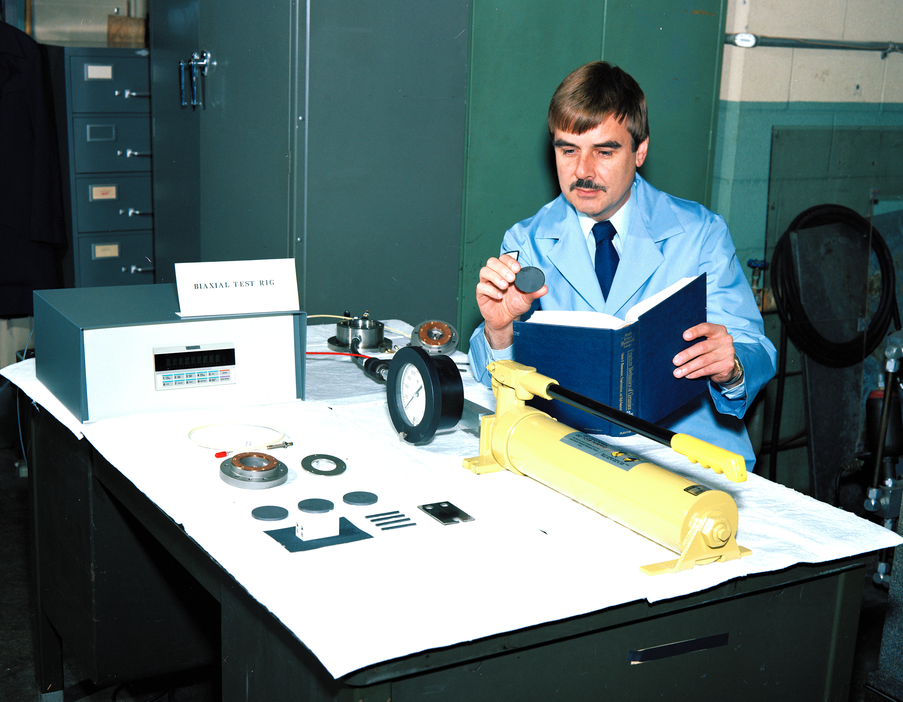 Man examining test specimens on table.
