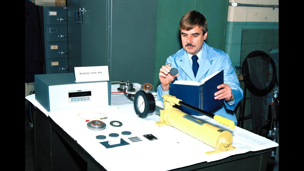 Man examining test specimens on table.