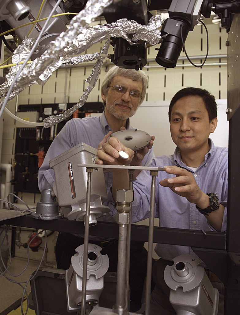 Two men examining test specimen.