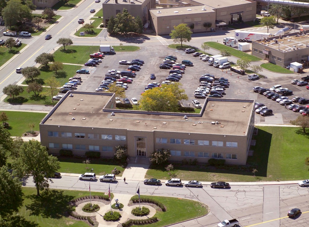 Aerial view of building with other buildings in background.