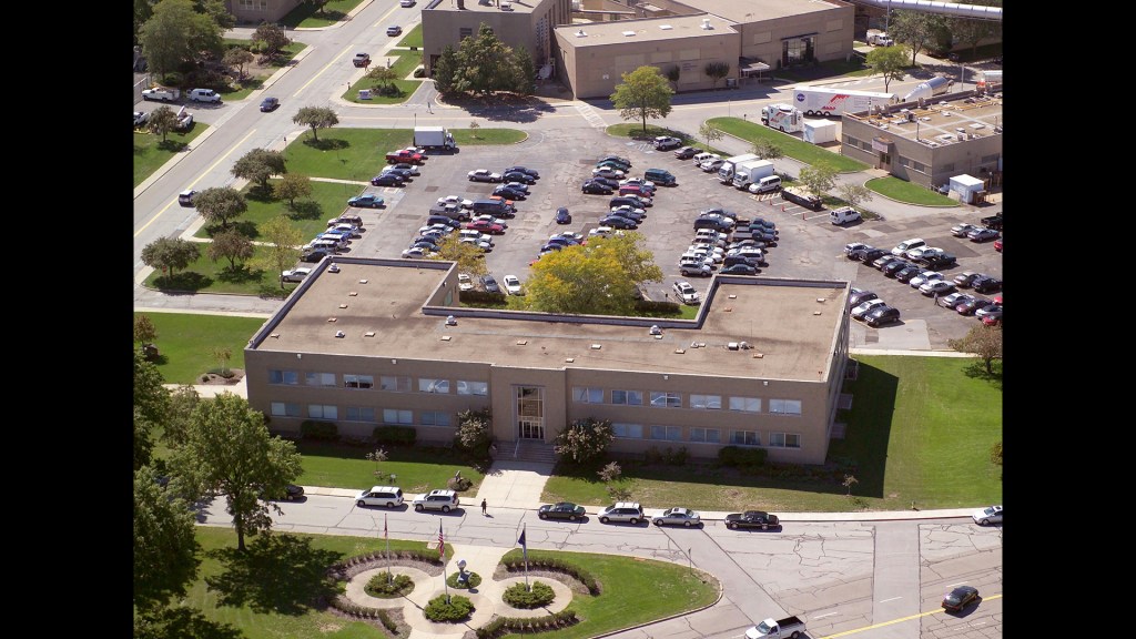 Aerial view of building with other buildings in background.