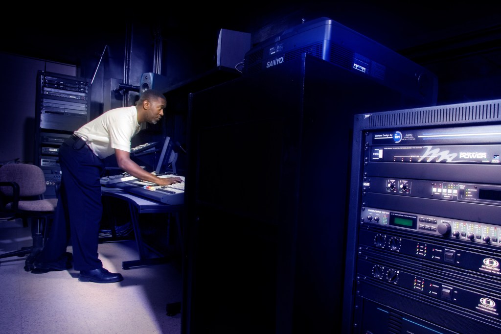 Man bent of console in dark room.