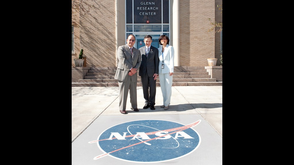 Two men and woman standing in front of building.