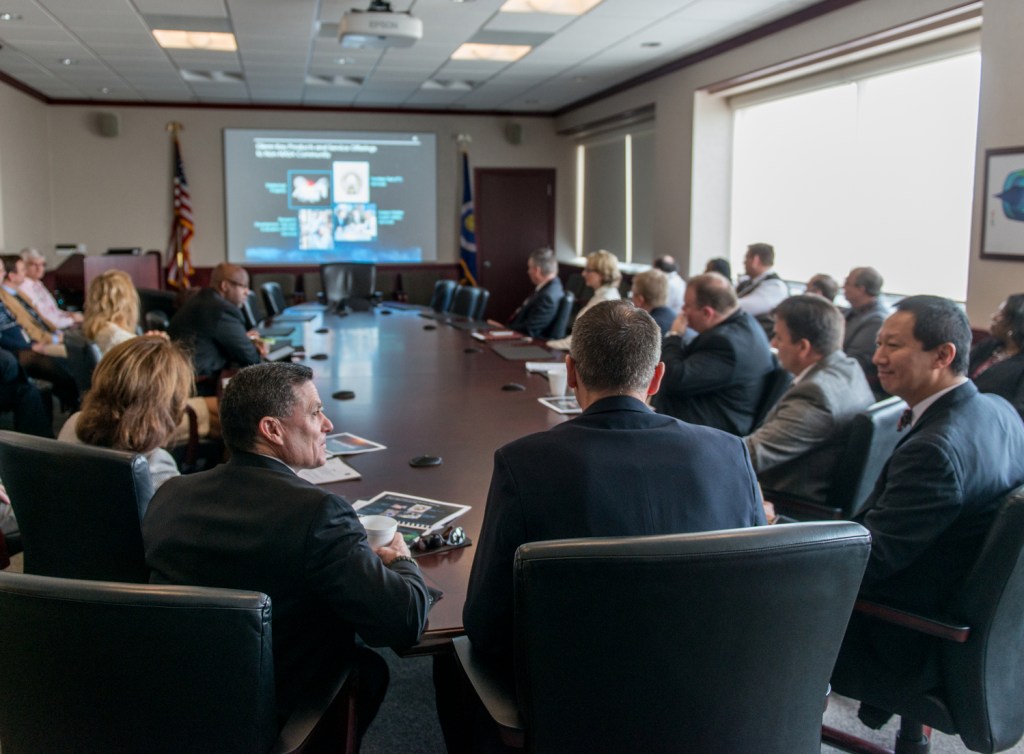 Group seated around table viewing screen.