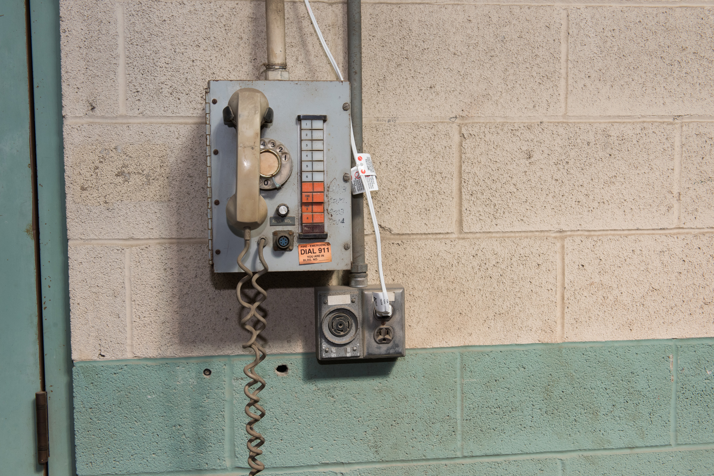 Telephone on cinder block wall.