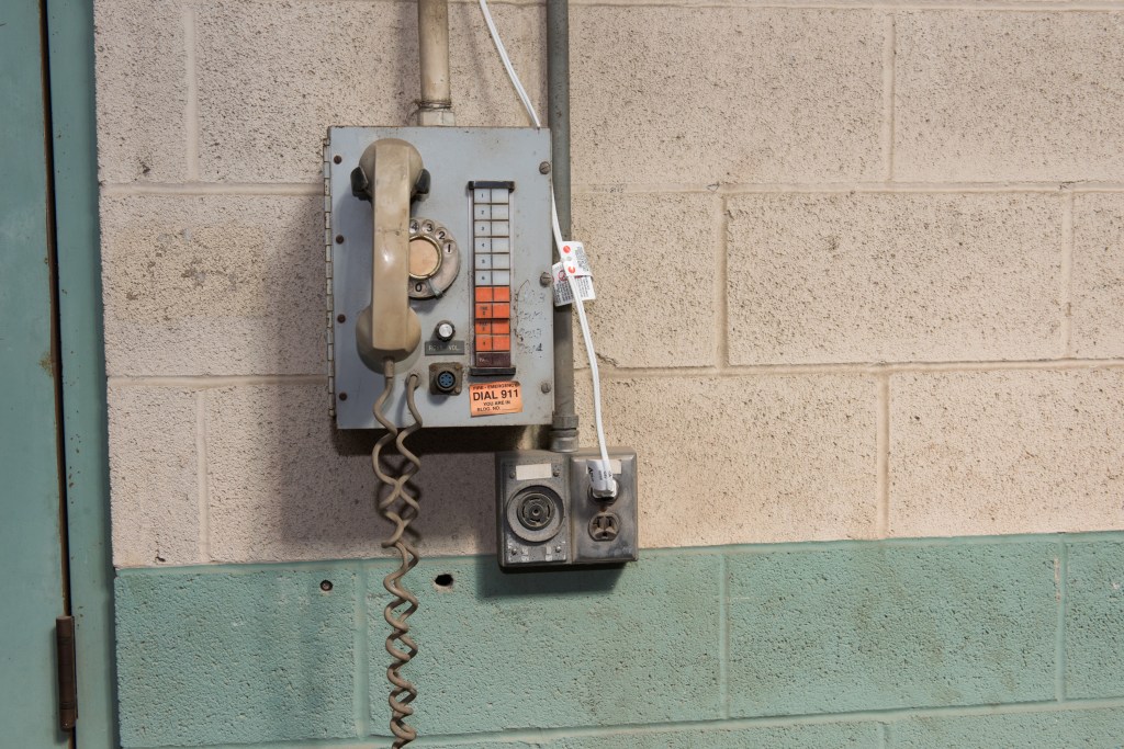 Telephone on cinder block wall.