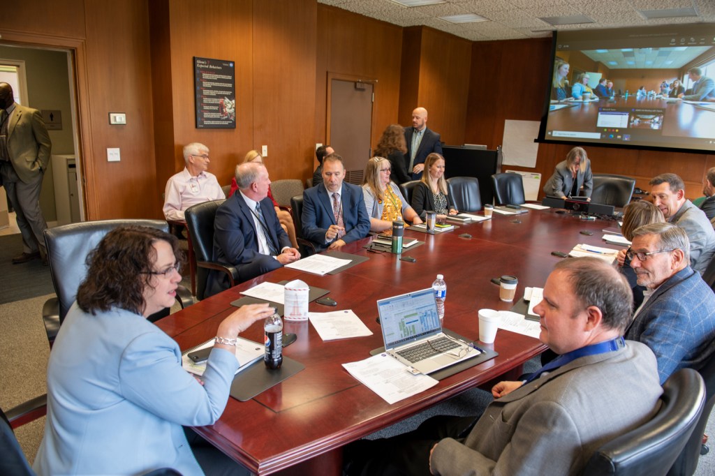 Group seated around table in conference room.