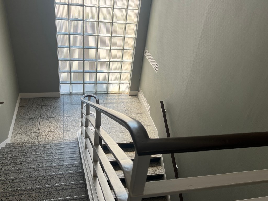 View down stairwell with glass block window in background.