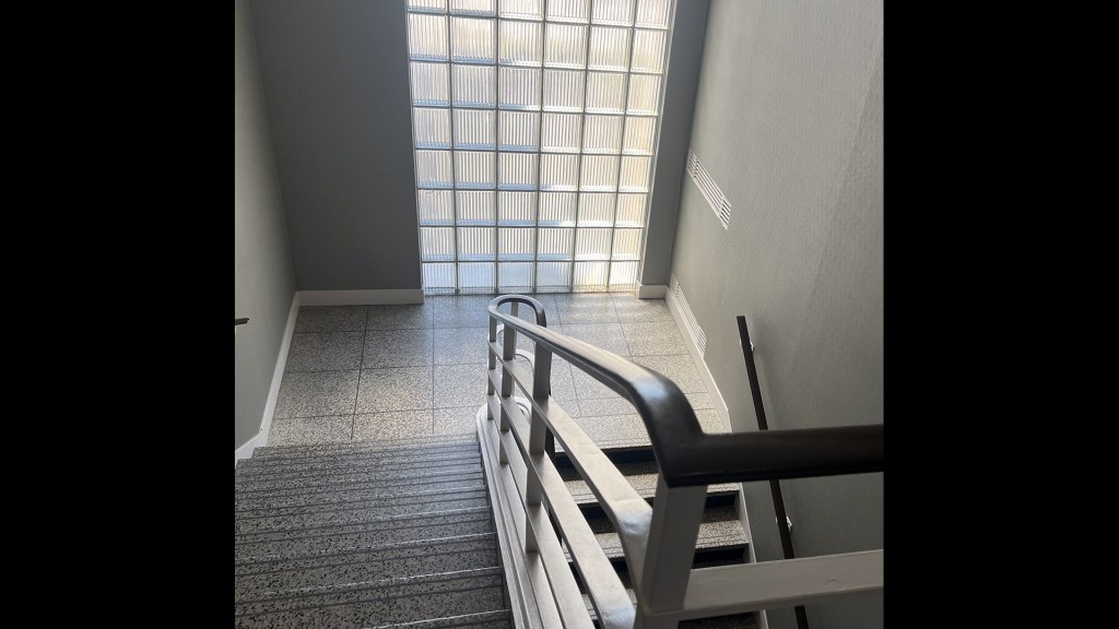View down stairwell with glass block window in background.