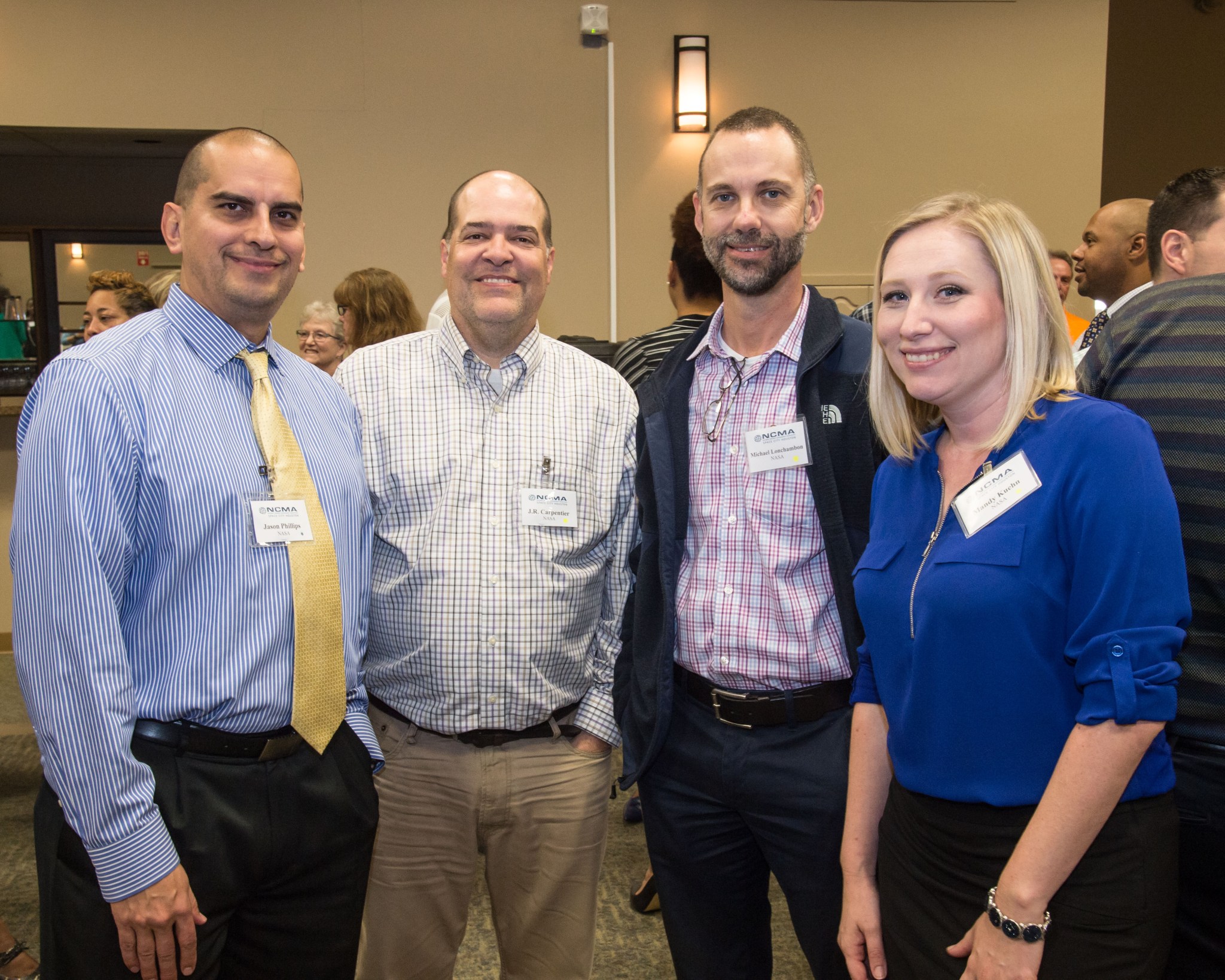 A group of four Johnson Space Center procurement employees poses for a photo during a procurement conference.