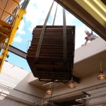 Crane lifting pallet through roof.