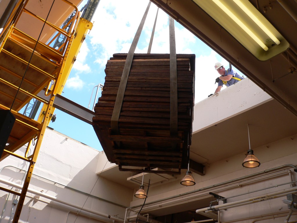 Crane lifting pallet through roof.