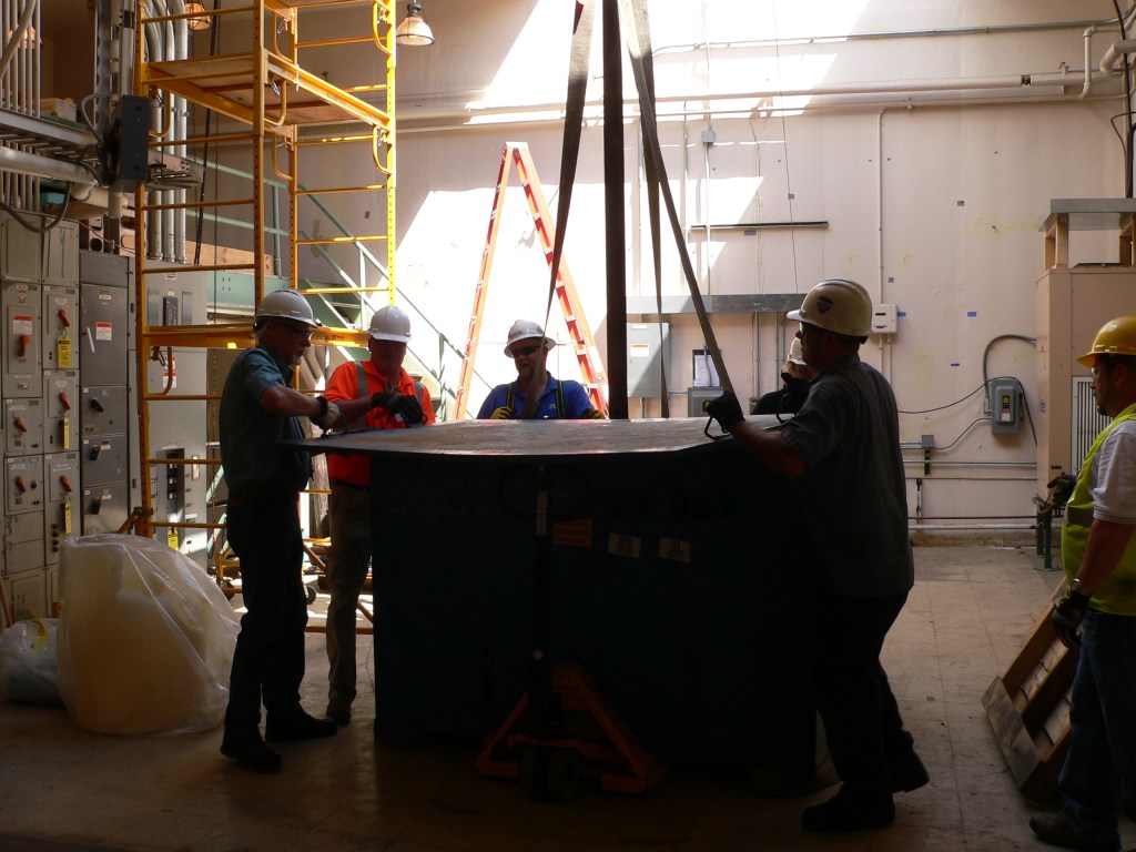 Men prepare load for crane lift.