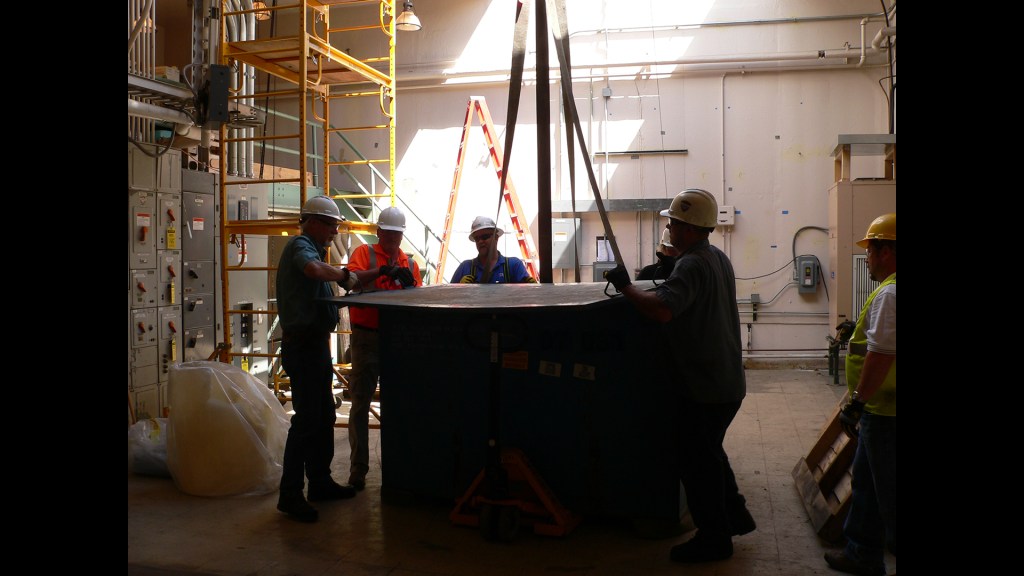 Men prepare load for crane lift.
