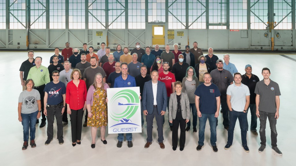 Quesst team group photo out at NASA Glenn inside a hangar.