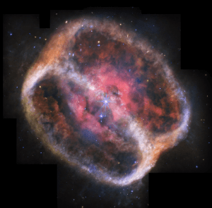 What looks like a single large, bright star (but is two) shines with bright purple diffraction spikes at the center of a large, diffuse cylinder of gas and dust that is tipped to the right. At the center is a bright pink clumpy cloud that takes up about 25% of the view. The pink region has some holes and diffuse areas. Beyond that are two large rings seen at a roughly 60-degree angle that appear joined at top left and bottom right. The edges are denser, and form shallow V-shapes that go inward. The rings appear orange at top left and bottom right, and are blue at bottom and center right. There is diffuse orange material around the body. The black background of space is speckled with tiny stars and galaxies mostly in blues and yellows. A bigger blue star with spikes is just below and to the left of the central stars, but it is slightly smaller. Areas Webb did not observe are along the top edges, a thin vertical near the nebula at top left, and at the bottom left and right corners.
