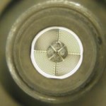 Close-up of a sensor with concentric circular patterns and small components in the center. The image is taken from a top-down perspective, showing intricate details of the device.