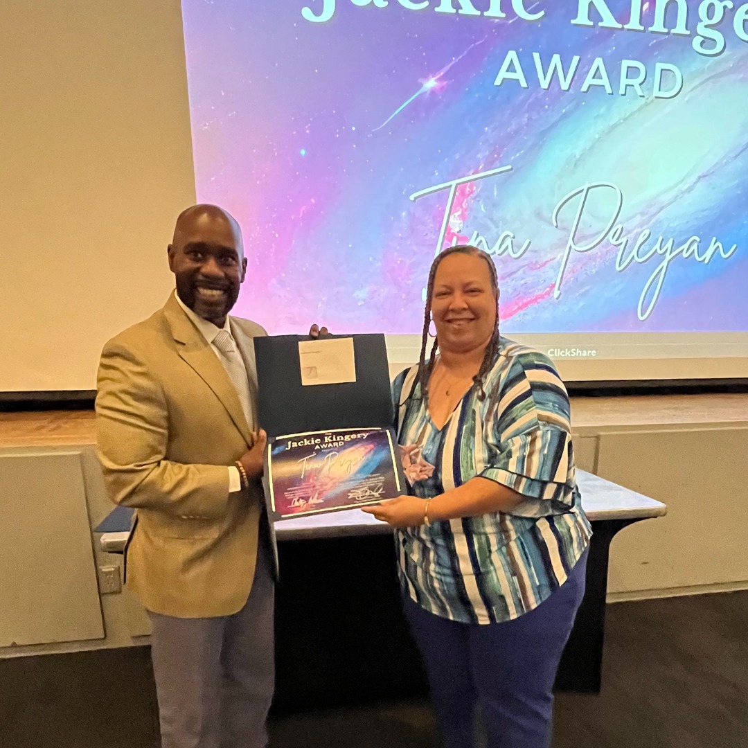 Johnson Space Center Food Services Specialist Tina Preyan receives an award from her manager in a meeting room.