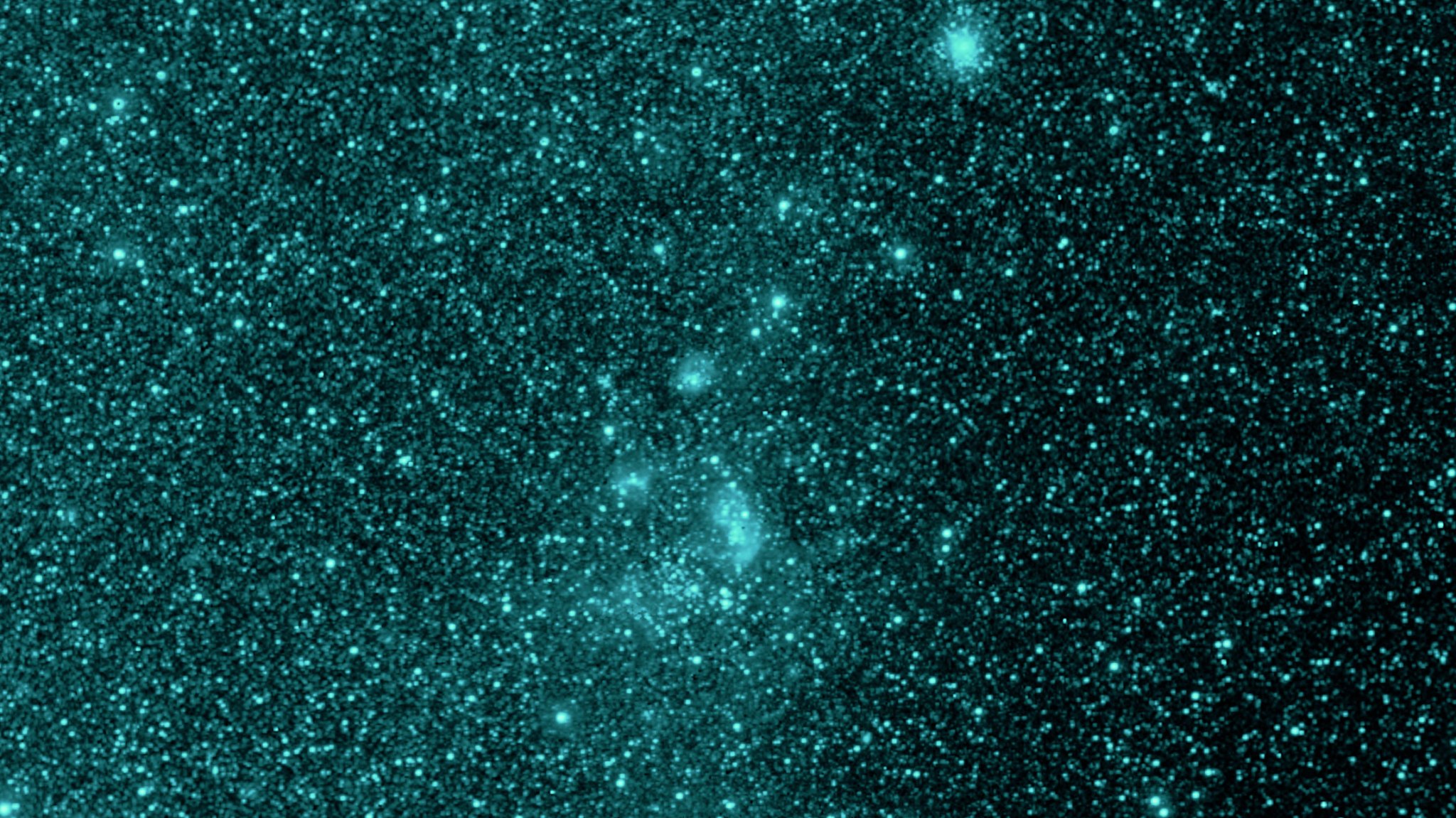 Infrared image showing a dense field of teal stars with faint, cloudy regions of interstellar dust, captured by NASA’s SPHEREx mission.