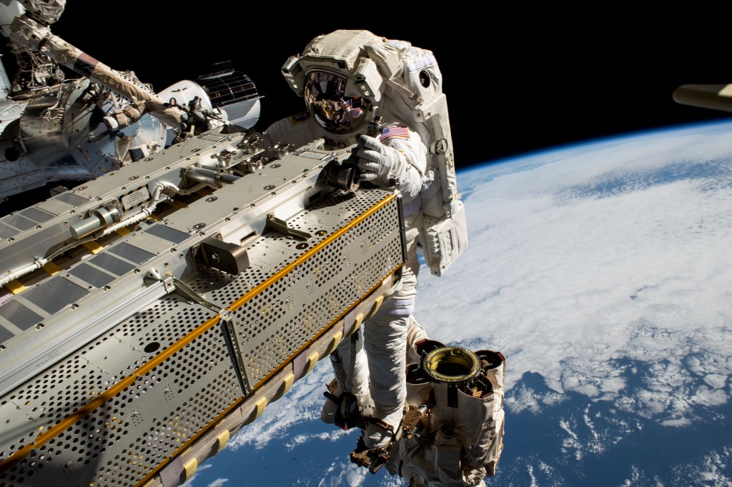 NASA astronaut and Expedition 68 Flight Engineer Woody Hoburg rides the Canadarm2 robotic arm while maneuvering a roll-out solar array toward the International Space Station's truss structure 257 miles above the Pacific Ocean. In the rear, is the SpaceX Dragon crew vehicle that docked to the Harmony module's forward port on March 3 carrying four SpaceX Crew-6 crew members.