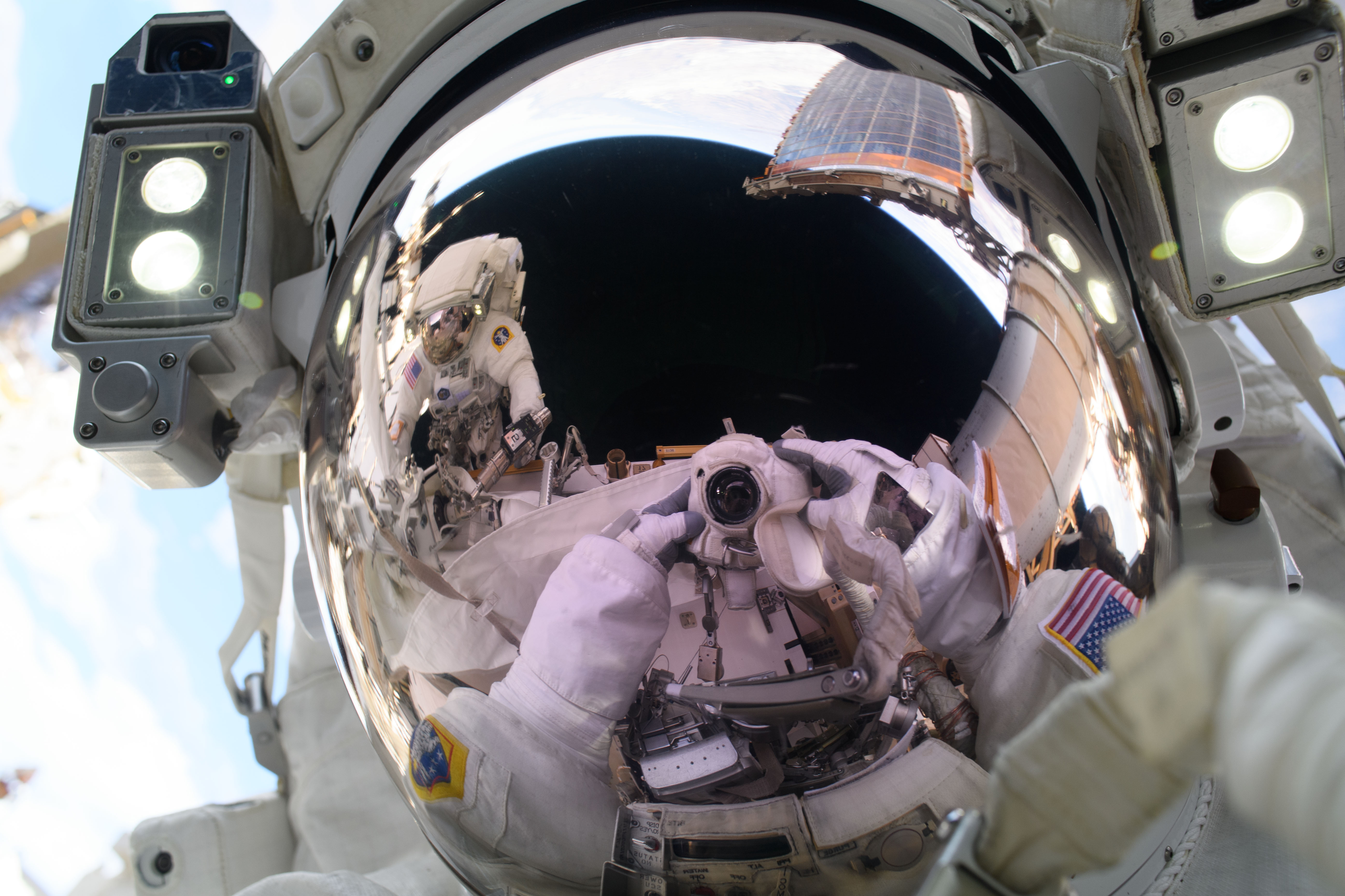 NASA astronaut and Expedition 72 Flight Engineer Anne McClain points a camera towards herself and takes a "space-selfie" during a spacewalk to upgr...