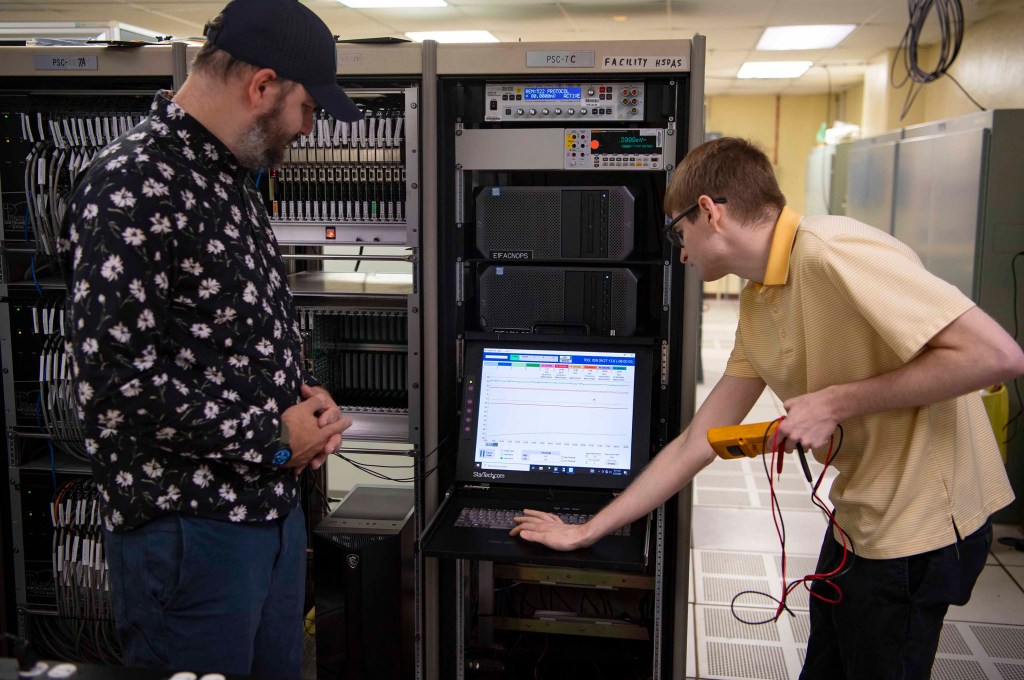 Two NASA engineers Steven Helmstetter, left, and Tristan Mooney work with the NASA Data Acquisition System in the E-1 Test Control Center