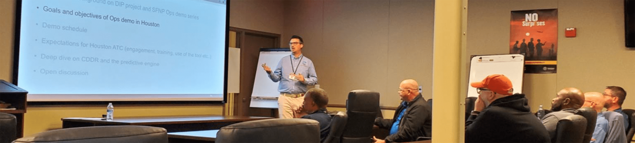 Image of 6 people sitting in a room, looking at a 7th person standing and going through a powerpoint, with caption reading "DIP meeting with FAA"