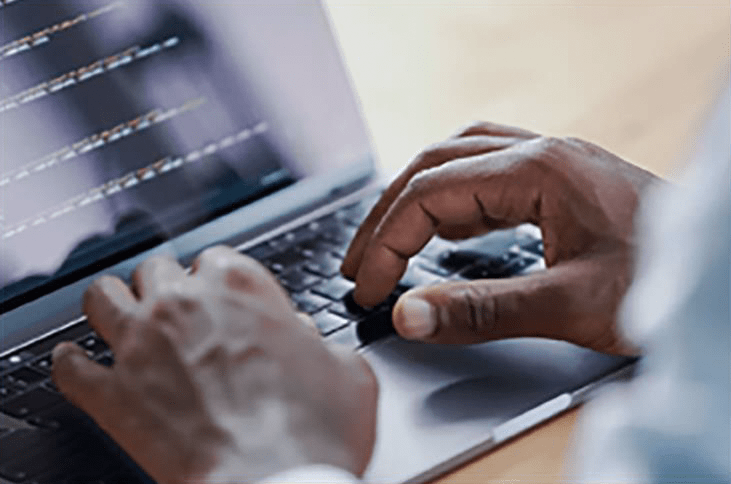 Stock photo of a man's hands on a laptop writing code.