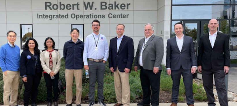 Image of 9 people smiling in front of a building with the title "Robert W. Baker: Integrated Operations Center", with the caption "DIP team and Collins Aerospace at American Airlines IOC"