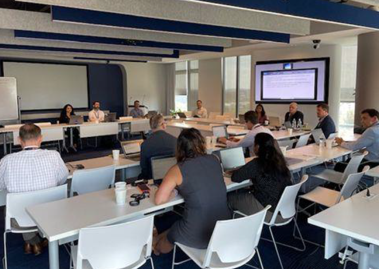Image of a room full of people sitting at tables on their laptops, with the caption "DIP TIM with FAA AES team in Washington DC"