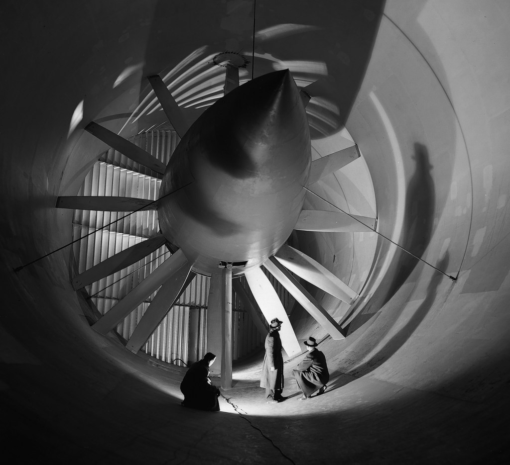 Two men in front of Altitude Wind Tunnel drive fan